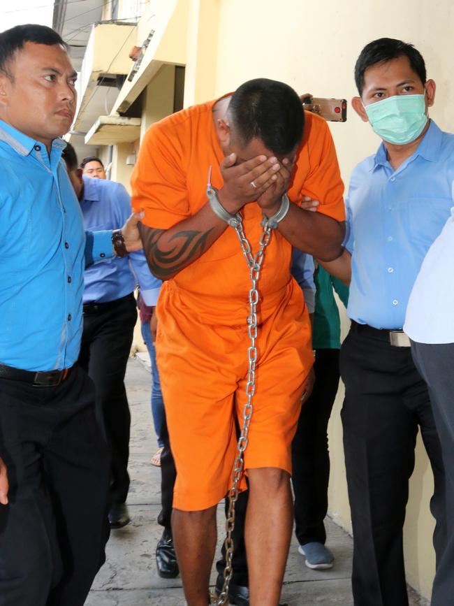 William Cabantog, 35, shields his face as he is escorted to the press conference. Picture: AAP Image/Lukman S. Bintoro