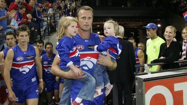 Western Bulldogs legend Chris Grant runs out with daughters Isabella and Sasha.