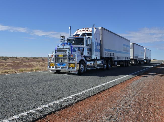 Coober Pedy, South Australia - May 20 2019: Three-trailer road train driving in central Australia Outback.Road train is a trucking vehicle used in remote areas of Australia,USA and Europe to move freight efficiently.