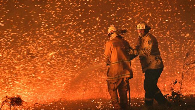 (FILES) This file picture taken on December 31, 2019 shows firefighters struggling against strong winds in an effort to secure nearby houses from bushfires near the town of Nowra in the Australian state of New South Wales. - Australia's unique wildlife is in retreat as it reels from bushfires, drought, human activity and global warming, according to a "shocking" government report on July 19, 2022 that prompted calls for dramatic change. (Photo by Saeed KHAN / AFP) / XGTY