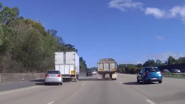 Dashcam footage has captured the moment a car swerved into the path of a semi-trailer on the M1 at Helensvale.