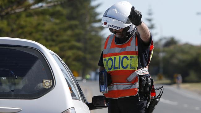 A police officer speaks with a driver after pulling them over for speeding. Picture: Simon Cross