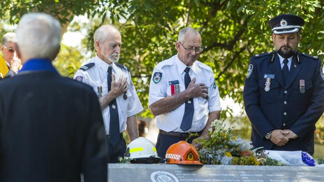 NSW Rural Fire Service members place their hands over their heart after laying flowers during the annual Emergency Service Volunteer Memorial at the Royal Botanic Garden in Sydney on Sunday. Picture: NCA NewsWire / Jenny Evans