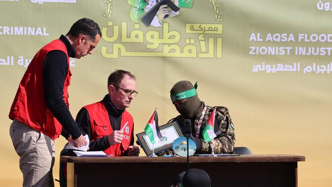 Red Cross staff sign a document with a Hamas fighter in Gaza City as they prepare to receive four Israeli hostages on Saturday. Picture: AFP