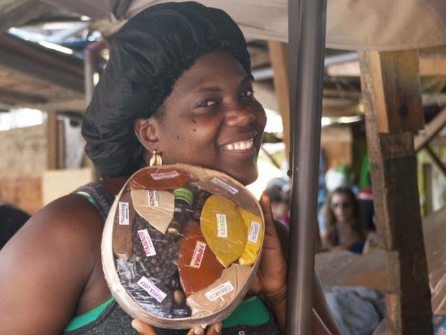 St. Georges, Grenada â€“ January 17, 2015: Smiling female market stall trader, looking into the camera, offers a pack of mixed local spices at the famous Saturday morning market in St. Georges, market square, Island of Grenada. Photo: iStock