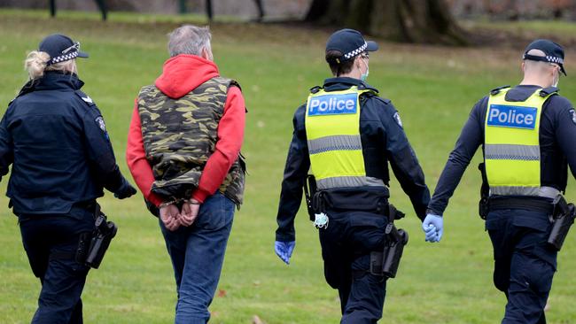 Police escort a handcuffed man from the scene. Picture: Andrew Henshaw