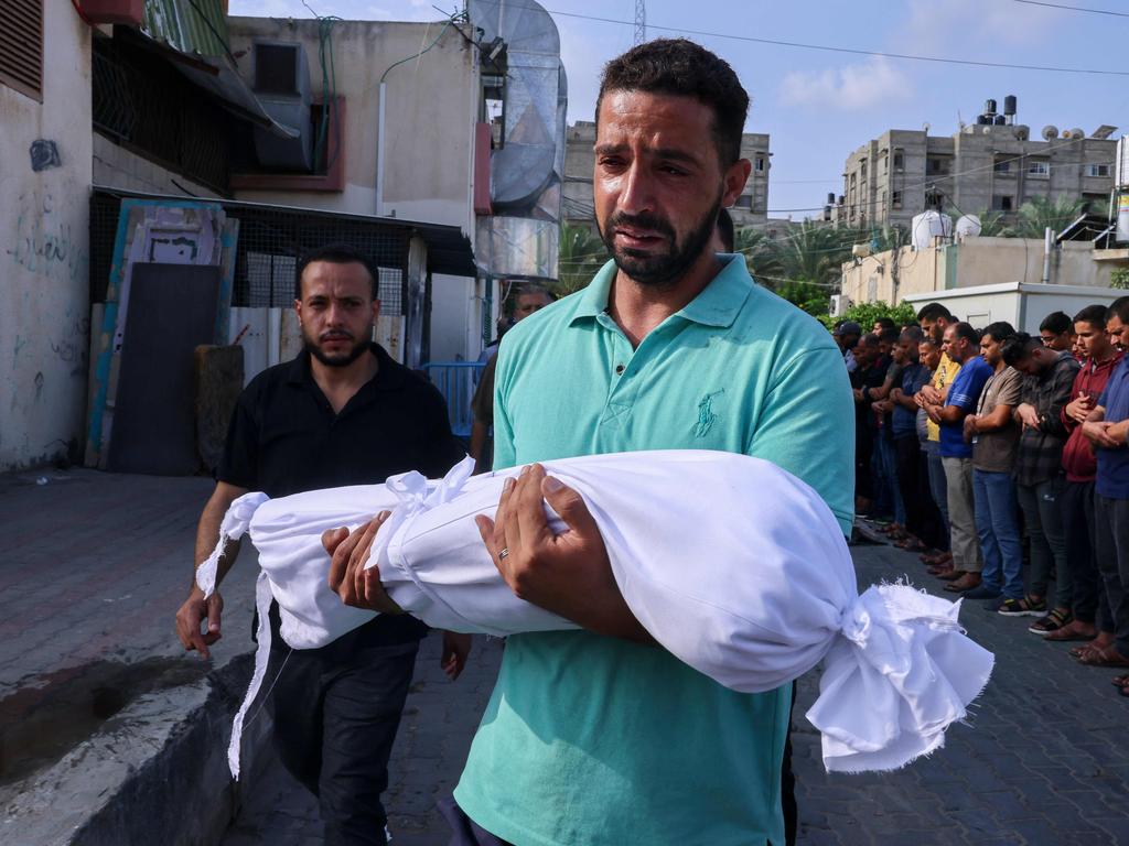 A Palestinian man carries the body of a child killed in overnight Israeli shelling. Picture: AFP