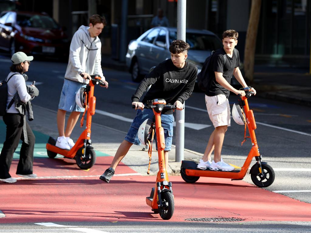 A group of teenage e-scooter riders without helmets in Brisbane. Picture: David Clark