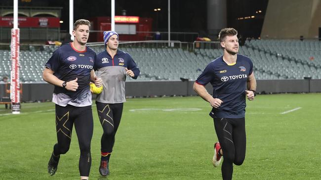 Josh Jenkins, Bryce Gibbs and Darcy Fogarty run laps of the Adelaide Oval after the Crows game on Saturday night. Picture SARAH REED