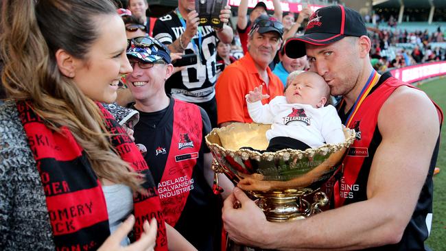 West Adelaide’s Jason Porplyzia celebrates the 2015 SANFL premiership win with his baby Rori and partner Becky Fisher.