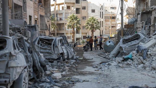 People and Syrian rescuers known as the White Helmets stand near building rubble at the site of a reported airstrike on a neighbourhood in Syria's rebel-held northern city of Idlib.