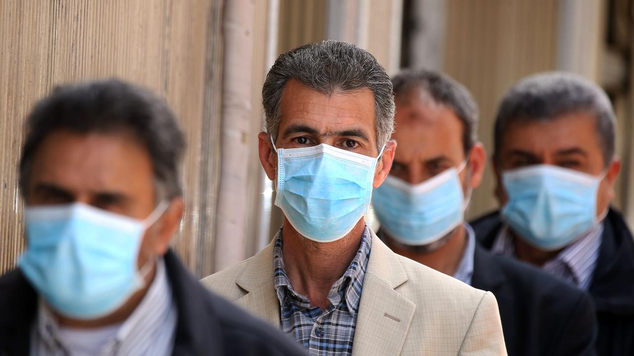 Men wearing masks as they wait outside in Tripoli. Picture: Mahmud Turkia/AFP