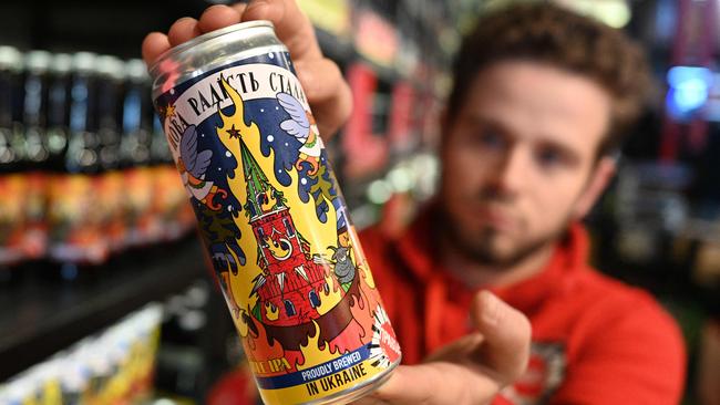 An employee of the Pravda beer bar in the western Ukrainian city of Lviv holds a home-brewed can of beer with labels depicting a burning Moscow Kremlin. Picture: AFP