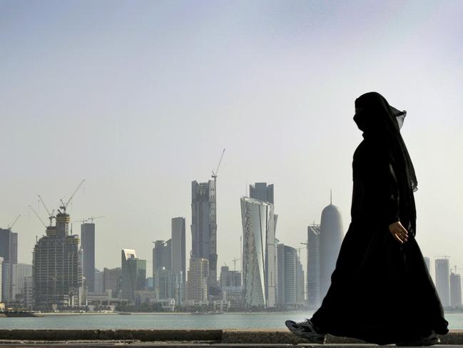 FILE - In this May 14, 2010 file photo, a Qatari woman walks in front of the city skyline in Doha, Qatar. Saudi Arabia and three Arab countries severed ties to Qatar on Monday, June 5, 2017 and moved to cut off land, sea and air routes to the energy-rich nation that is home to a major U.S. military base, accusing it of supporting regional terror groups. (AP Photo/Kamran Jebreili, File)