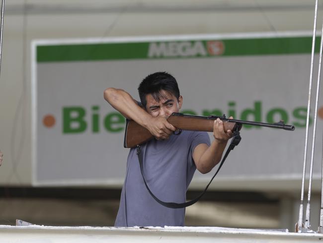 An employee fires a rifle at people trying to loot the store.