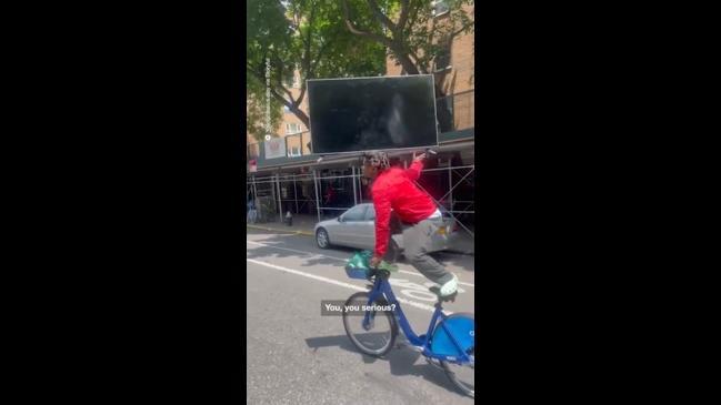 Man rides bike with TV on his head