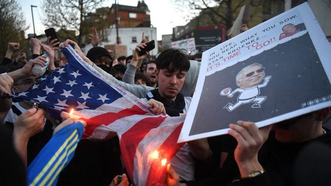 Supporters try to set alight a US flag as they protest against Arsenal's US owner Stan Kroenke. (Photo by DANIEL LEAL-OLIVAS / AFP)