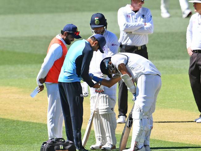 India's Mohammed Shami (C) receives treatment on his arm before retiring hurt on the third day of the first cricket Test match between Australia and India in Adelaide on December 19, 2020. (Photo by William WEST / AFP) / --IMAGE RESTRICTED TO EDITORIAL USE - NO COMMERCIAL USE--