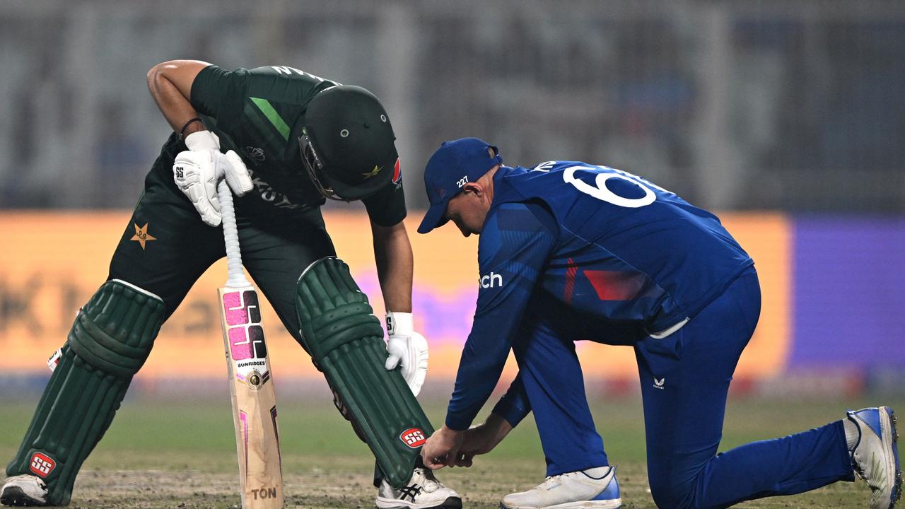 England's Joe Root (R) ties the shoelace of Pakistan's Mohammad Rizwan. Photo by Arun SANKAR / AFP.