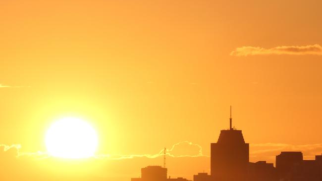 The sun sets over Sydney Harbour, with the outline of skyscrapers and residential towers of Milsons Point and North Sydney. (iStock)