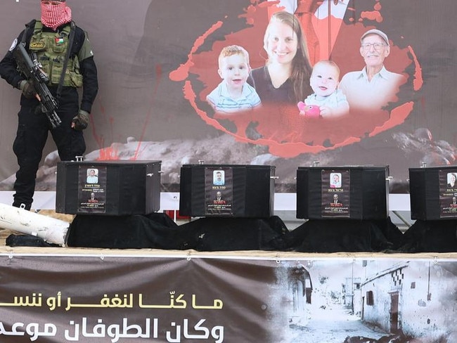 Armed Hamas militants stand next to the coffins on stage before handing over the bodies of four Israeli hostages to the Red Cross in Khan Yunis