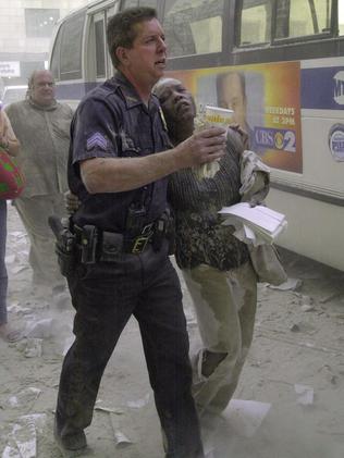 A police officer helps a woman to a bus after she fled the area near the World Trade Centre towers.