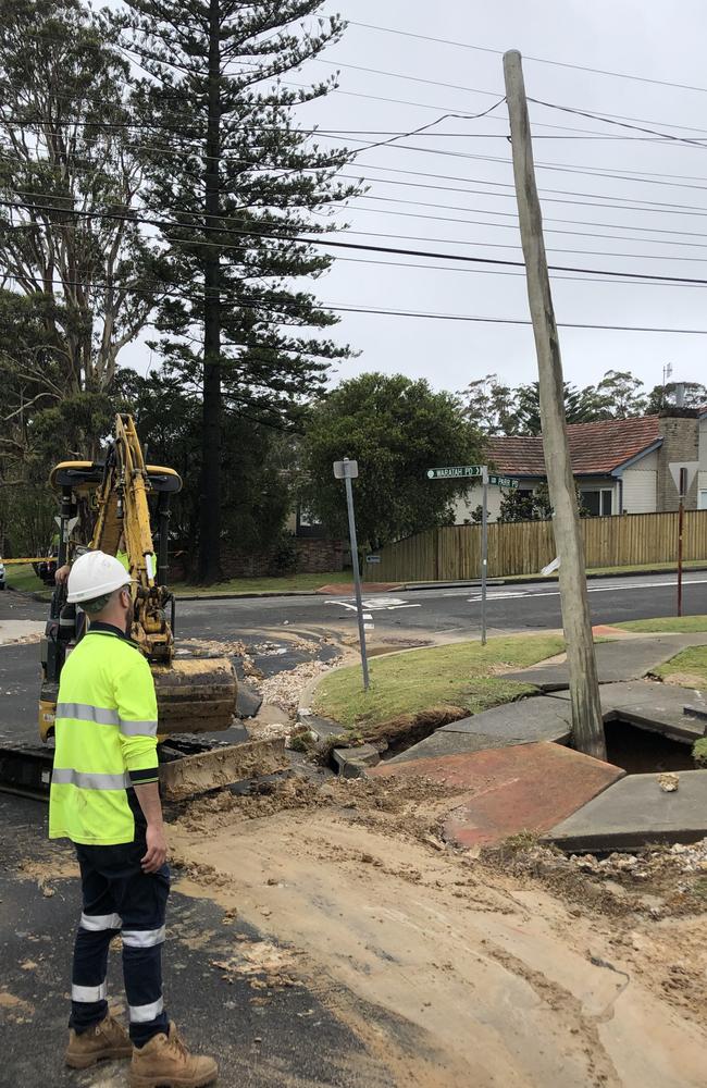 A power pole was left leaning precariously after it was undermined by water from a burst main that smashed through the footpath at the corner of Parr and Waratah parades at Narraweena on Tuesday morning. Picture: Jim O'Rourke