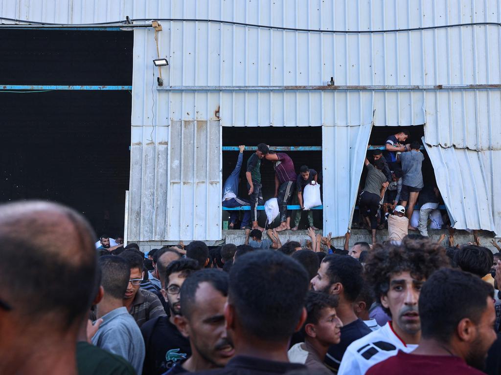 Displaced Palestinians rip off parts of the building as they storm the World Food Programme warehouse in Deir el-Balah. Picture: AFP