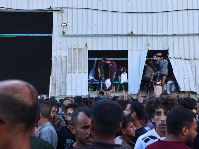 Displaced Palestinians rip off parts of the building as they storm the World Food Programme warehouse in Deir el-Balah. Picture: AFP
