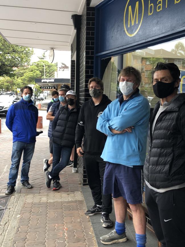 Ian Jessup, in blue, from Queenscliff, and Rafa Galego, (right) of Dee Why, at the head of the queue for a haircut at M Barber in Darley St, Manly. Picture: Jim O'Rourke