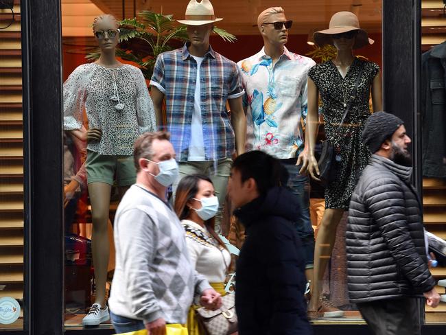 Pedestrians, some wearing face masks, walk through Sydney's central business district this week as the city’s virus numbers remain in single digits. Picture: AFP