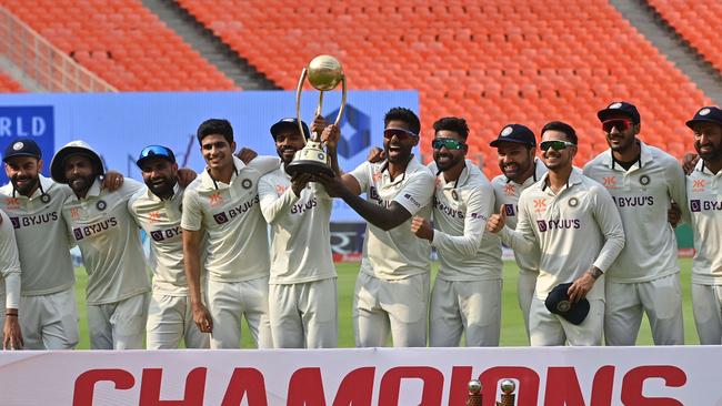 India's players pose with the trophy after winning the series. (Photo by Punit PARANJPE / AFP)