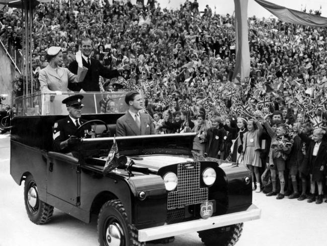 Queen Elizabeth II and the Duke of Edinburgh Prince Philip stand in a moving vehicle and wave to Adelaide crowds during the 1954 tour.