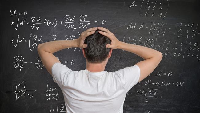 Young man is solving mathematical problem on blackboard and is confused.