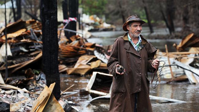 Mogo leather shop owner Gaspar stands amongst the remains of his recently burnt out shop now submerged in flood waters from torrential rains. Picture: Jane Dempster/The Australian.