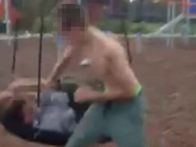 One of the attackers punches the prone victim while he is trapped on the swing.