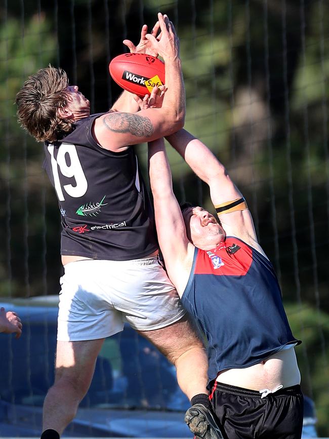 Omeo-Benambra’s James Gibbs launches over a Swifts Creek opponent. Picture Yuri Kouzmin