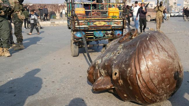 A truck pulls the head of the toppled statue of late Syrian president, Hafez al-Assad, through the streets of the captured central-west city of Hama. Picture: AFP