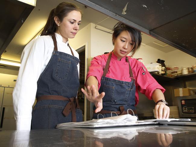 New job ... Head Chef Christy Tania explains a desert recipe to Ashleigh Bareham in the kitchen at Om Nom. Picture: David Caird.