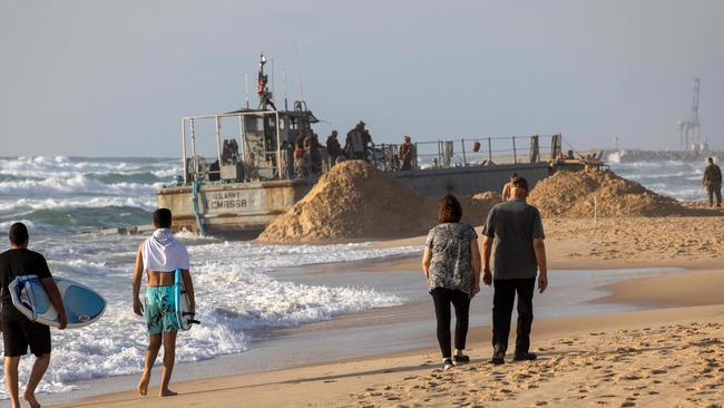 Israelis walk near a US Army vessel at that ran aground as it supported a temporary pier built to deliver aid to Gaza by sea. Picture: AFP.