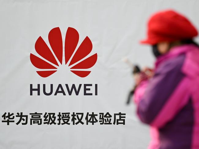 A woman using her smartphone while walking past advertising outside a Huawei store in Beijing. — The founder of Chinese telecom giant Huawei has hit back at US efforts to blacklist the company, saying defiantly that the world cannot do without Huawei and its "more advanced" technology. Picture: AFP