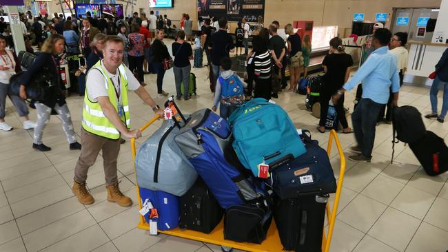 Gold Coast Airport CEO Chris Mills loading luggage during one of the busiest days ever for the airport. Picture Glenn Hampson