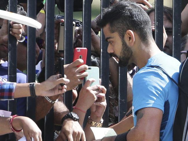 India's Virat Kohli signs autographs for fans at a gate of the Sydney Cricket Ground during training for the Cricket World Cup in Sydney, Australia, Wednesday, March 25, 2015. India will play Australia in the World Cup semifinal on Thursday March 26, 2015 to gain a place in the final against New Zealand.(AP Photo/Rob Griffith)