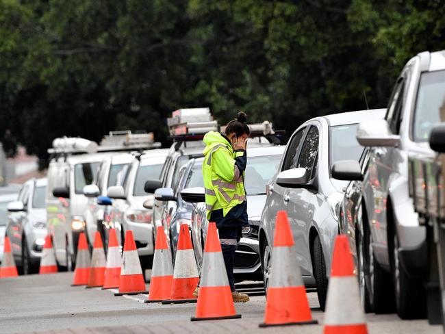 A traffic warden manages a queue of cars outside a drive-through Covid-19 testing clinic in Sydney's Fairfield suburb on July 14, 2021. (Photo by Saeed KHAN / AFP)