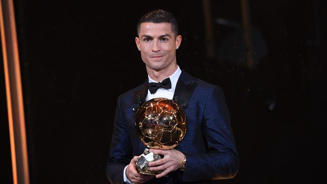Cristiano Ronaldo posing with the Ballon d'Or France Football trophy.