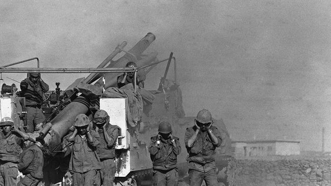 Israeli soldiers plug their ears as they fire shells from a French-made 155mm Horwitzer gun at the Syrian front lines on the Syrian Golan Heights during Yom Kippur War on October 17 1973.