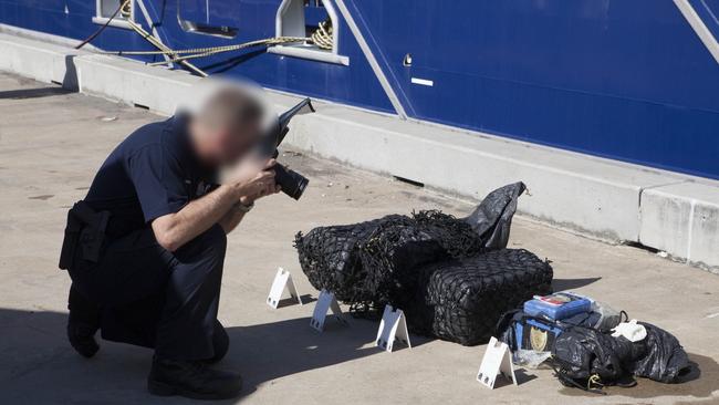 A police officer photographs evidence linked to the alleged drug smuggling case.