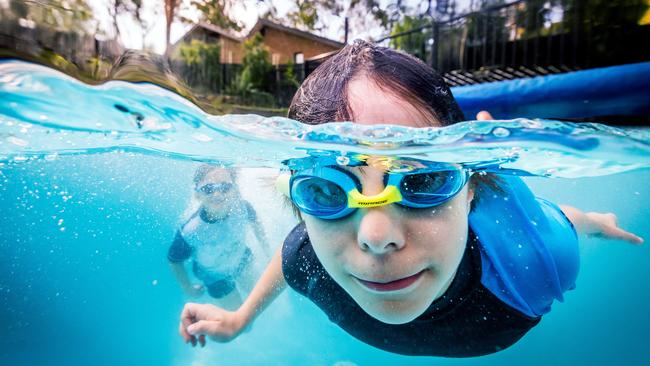 Remi and Oliver swim in a backyard pool. Picture: Jake Nowakowski