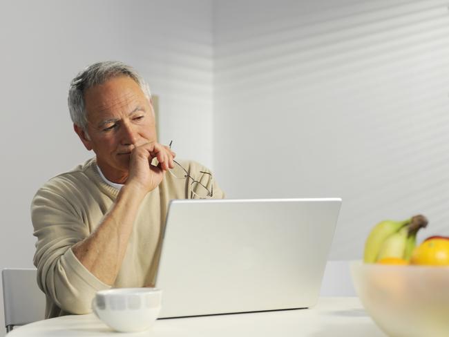 Undated : Istock - baby boomers - older / middle-aged man sitting at a laptop computer, glasses in his hand, cup of coffee, bowl of fruit