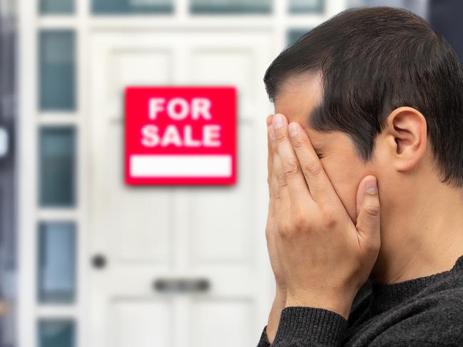 Man extremely depressed and sad about losing his house key and seeing a for sale sign, real estate concept; first home buyer generic sad, stressed